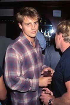 two men standing next to each other at a bar with one holding a piece of chocolate