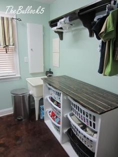 an organized laundry room with clothes hanging on the rack and other items in bins