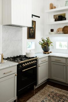 a kitchen with white cabinets and marble counter tops, gold trim on the oven hood