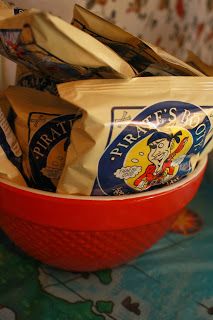 a red bowl filled with bags of chips on top of a table next to a wall