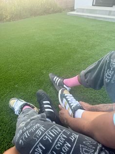 two people are sitting on the grass with their feet up and one person is wearing socks