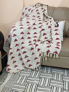 a couch with a blanket on top of it next to a chair and rugs