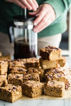 there are many pieces of cake on the counter next to a coffee maker and some cookies