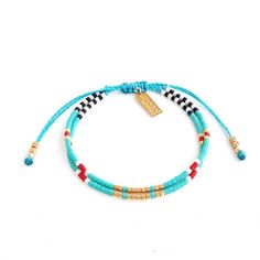 the turquoise and gold beaded bracelet is shown with an arrow charm on it's end