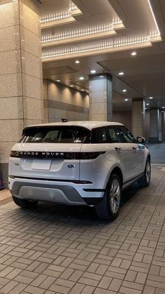 an suv parked in front of a building with lights on it's ceiling and two people standing next to it