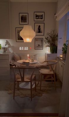 a table and chairs in a small room with pictures on the wall above it, next to a window