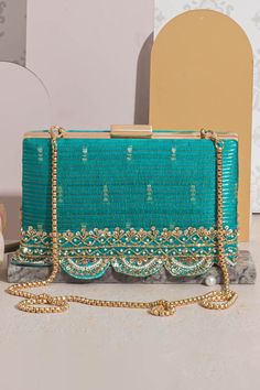 "Introducing Tari, a collection of exquisite raw silk potlis and clutches. Comes in an array of vibrant colors including regal purple, pink, mehndi green, warm mustard, and turquoise. The potli and the clutches are adorned with a delicate handcrafted embroidered border. The richness of material, captivating colors, and intricate details are an homage to South India. Perfect for all occasions, weddings, functions, and festive celebrations. Color: Turquoise Embroidered front and back. Dimensions (LxB): 7.75\"x4.5\" (19.7 cm X 11.4 cm) Handle length: 47\" (120 cm) Handle drop: 23\" (58 cm) Material: Embroidered pure silk, tissue inner lining, gold embroidered border lace, poly satin lining, gold metal clutch frame, gold metal sling. Features: metal lock closure, detachable metal sling." Elegant Diwali Raw Silk Embroidered Fabric, Elegant Embroidered Fabric With Gota Work For Diwali, Elegant Diwali Embroidered Fabric With Gota Work, Elegant Embroidered Fabric For Diwali, Elegant Embroidered Fabric For Diwali Festivities, Elegant Raw Silk Embroidered Fabric For Party, Celebration Tussar Silk Fabric With Zari Embroidery, Tussar Silk Fabric With Zari Work For Celebration, Festive Silk Thread Embroidered Fabric For Celebration