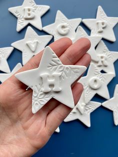 a hand holding a white ceramic star ornament in front of many smaller ones