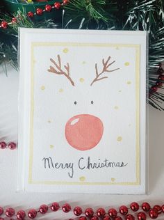 a christmas card with reindeer's nose on it and red balls around the edges