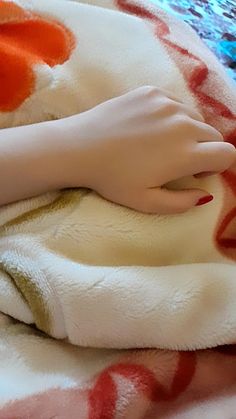 a person's hand on top of a white and red blanket with orange circles