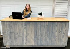 a woman sitting at a desk with a laptop computer on top of it, in front of a garage door