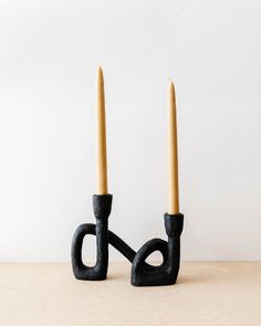 two candles sitting on top of each other in front of a white wall and one is black