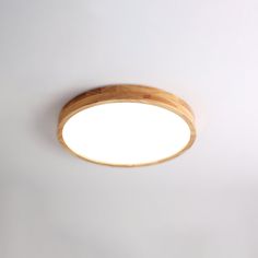 a light that is on the ceiling with a white wall in the background and a wooden frame around it