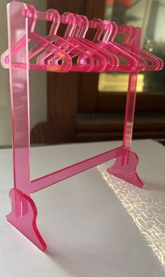 there is a pink rack with clothes hanging from it's sides on the table