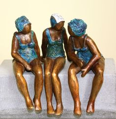 three bronze figurines sitting next to each other