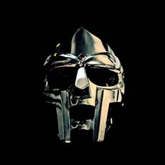 a metal mask with two knives sticking out of it's face, against a black background