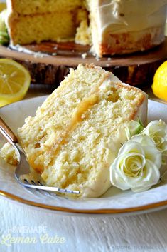 a slice of lemon cake on a plate with a fork next to it and flowers