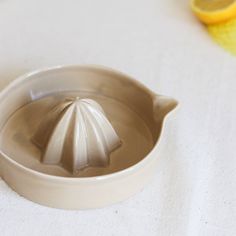 a white ceramic teapot with a yellow lemon in the background on a white tablecloth