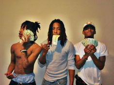 three shirtless men holding money in front of their faces while standing next to each other