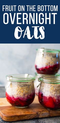 three jars filled with fruit on the bottom and overnight oats in them, sitting on a cutting board