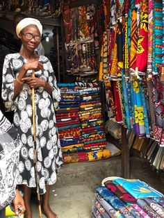 a woman standing in front of a store looking at her cell phone while wearing a headscarf