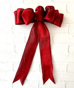 a red bow hanging on the side of a brick wall