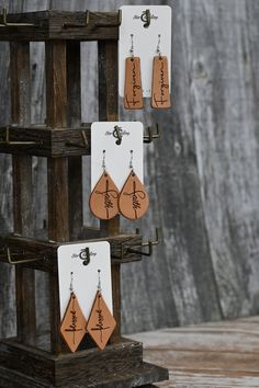 three wooden earrings are hanging from hooks on a rack in front of a wood wall