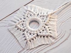 a piece of white yarn with a circular hole in the middle on a wooden surface