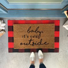 a person standing in front of a door mat that says baby it's cold outside