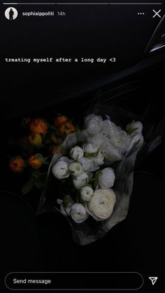 a bouquet of white roses sitting on top of a black table next to a cell phone