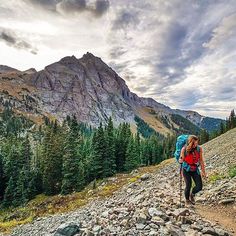 a woman hiking up a rocky trail in the mountains