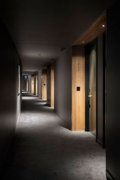 an empty hallway with wooden doors and black walls