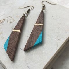 two wooden earrings with blue and brown designs on them