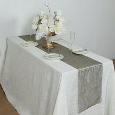 the table is set with white flowers and silverware on it, along with two wine glasses