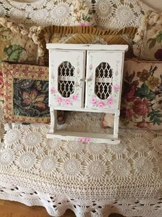 a doll house is sitting on top of a crocheted doily covered bed