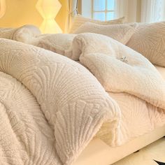 an unmade bed with white comforters and pillows