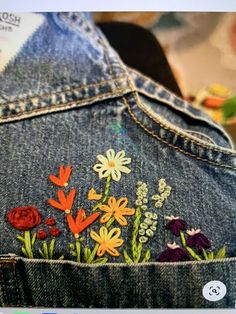 the back of a jean jacket with embroidered flowers on it and an image of a cat