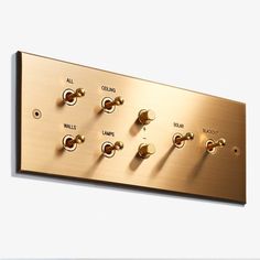 a gold plate with six different knobs and two switches on each side, mounted to the wall