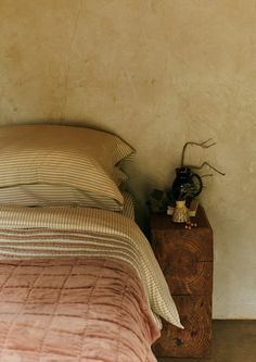 a bed sitting next to a wooden nightstand with a clock on it's side