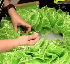 a person is working on some bright green mesh material with scissors and yarn in front of them