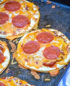 four pepperoni pizzas sitting on top of a baking sheet