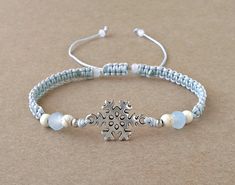 This Snowflake Bracelet is made with silver antique charm, light gray synthetic satin cord, howlite beads, glass beads, and silver antique beads.  It is perfect as a gift for Christmas or Winter. It is also great for a friend or someone you love. SIZES: Snowflake Charm: 12 mm x 12 mm Synthetic Satin Cord: 0.9 mm Light Blue Beads: 4 mm x 5 mm Howlite White Beads: 4 mm  White Beads: 3 mm Silver Antique Beads: 2 mm Adjustable size in length with a sliding macrame knot. Expands from 16 to 26 cm. Let Winter Bracelet, Snowflake Bracelet, Ankle Bracelets Diy, Braided Bracelet Diy, Schmuck Diy, Pretty Jewelry Necklaces, Bracelet Christmas, Diy Friendship Bracelets Patterns, Diy Bracelet Designs