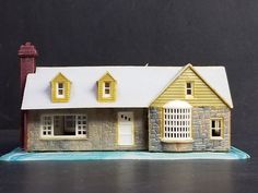 a small model house with a red chimney and white roof, sitting on a table