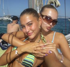 two beautiful young women sitting next to each other on a boat