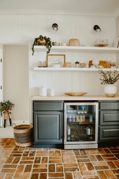 an open refrigerator in the middle of a kitchen with shelves above it and plants on top