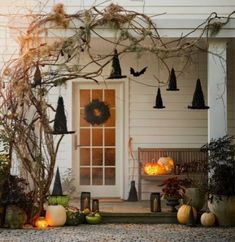 a front porch decorated for halloween with pumpkins and witch hats hanging from the branches