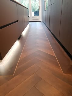 an empty kitchen with wooden floors and cabinets