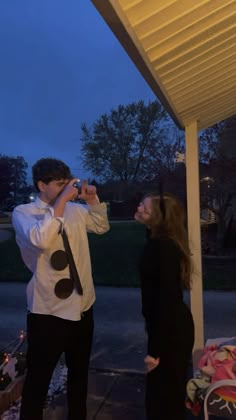 a man standing next to a woman on top of a porch