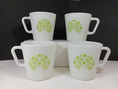 four white cups with green designs on them