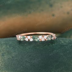 an emerald and diamond ring on top of a green surface